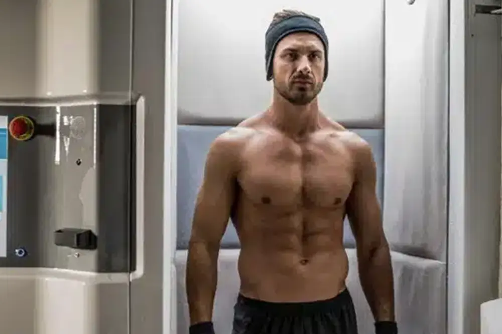 A muscular man engaging in a cryotherapy treatment procedure